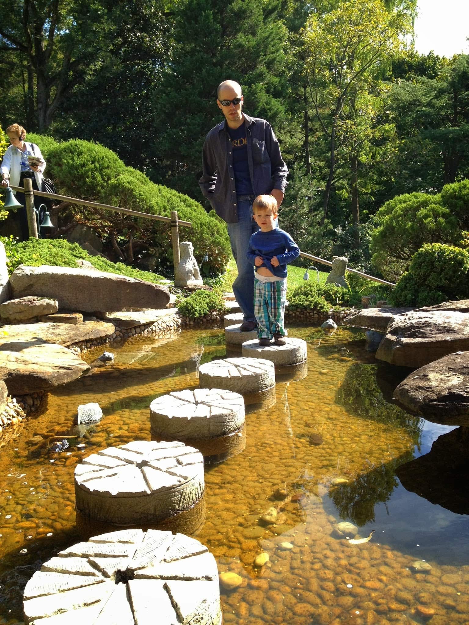 A boy and his father walk across a water feature in a popular DC garden next on the Hillwood Estate.